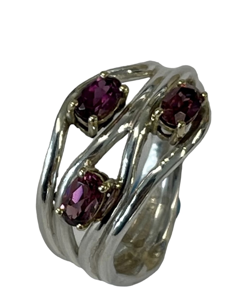 Silver dress ring with three faceted oval rhodolite garnets in four-claw yellow-gold settings on a split silver multi-band shank